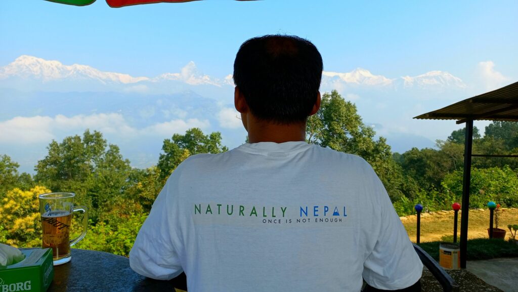 Hikers walking toward the World Peace Pagoda (Shanti Stupa) in Pokhara, Nepal, with scenic views of Phewa Lake and the Annapurna mountain range in the background.
