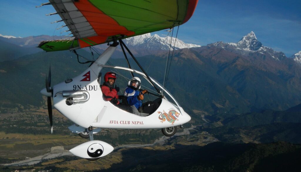 Ultralight aircraft flying above Pokhara Valley with panoramic Himalayan views in the background